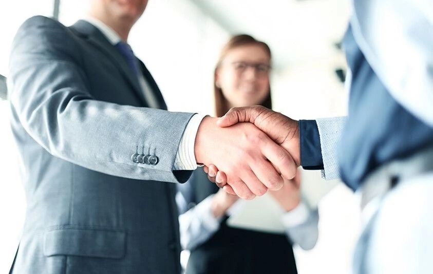Business professionals shake hands in a modern office setting